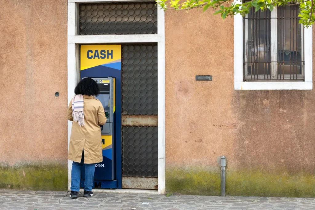 Žena si vyb&iacute;r&aacute; na ulici pen&iacute;ze z bankomatu Euronet