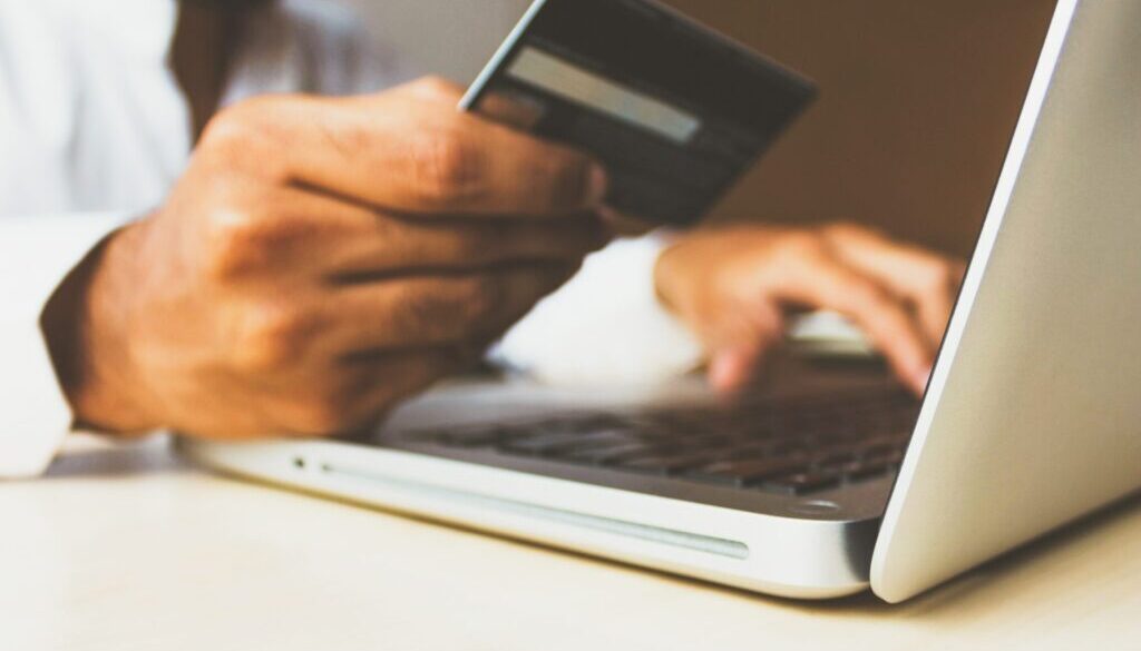 person using laptop computer holding card