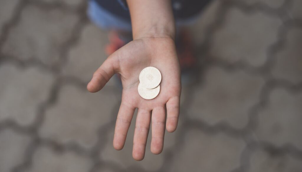 selective focus photography of person's palm with two coins