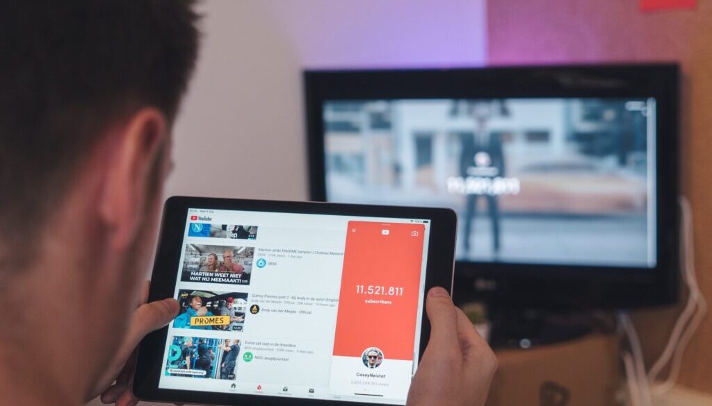 man browsing tablet sitting in front of TV