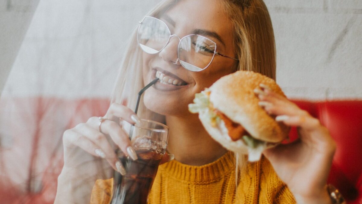 woman sitting while holding burger