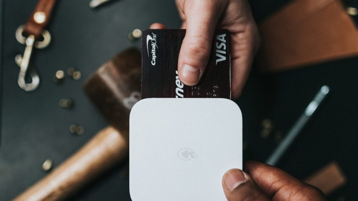 person holding Visa card and white device