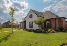 white and brown house near green grass field under white clouds and blue sky during daytime