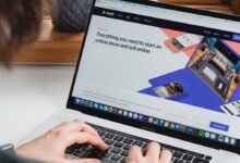 person using macbook pro on white table