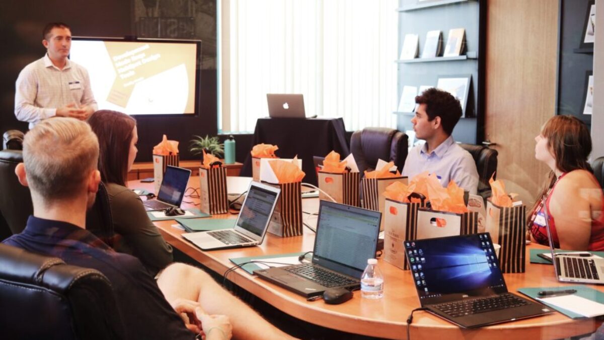 man standing in front of people sitting beside table with laptop computers