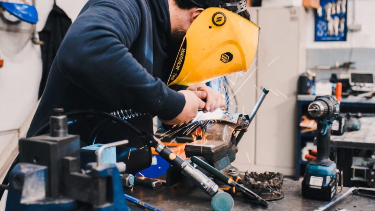 man wearing black hoodie using welding tool