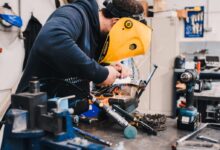 man wearing black hoodie using welding tool