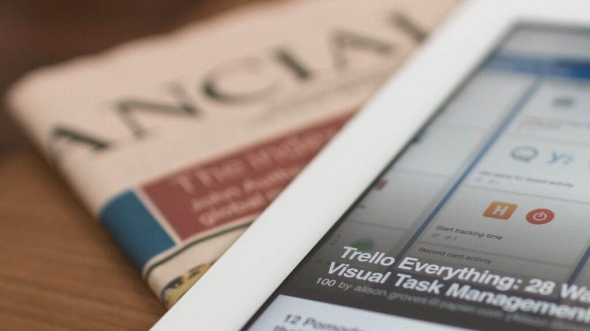 white tablet computer on top of newspaper