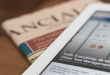 white tablet computer on top of newspaper