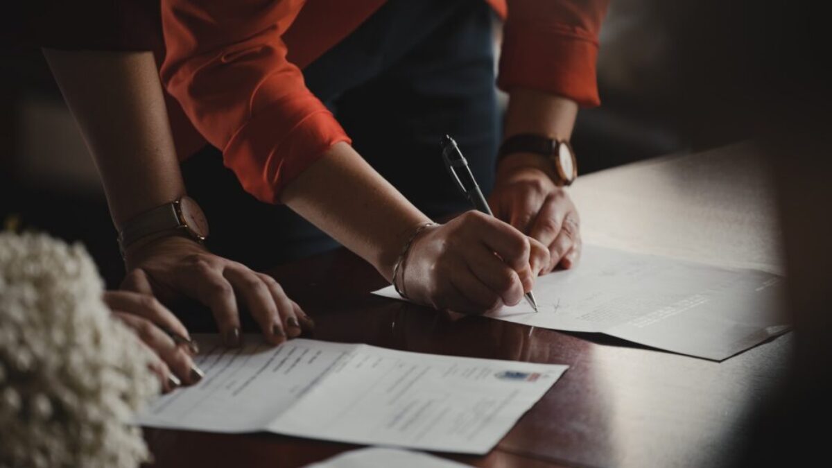 person in orange long sleeve shirt writing on white paper