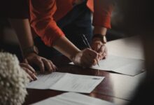 person in orange long sleeve shirt writing on white paper