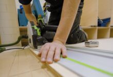 person in gray t-shirt holding green and white plastic tool