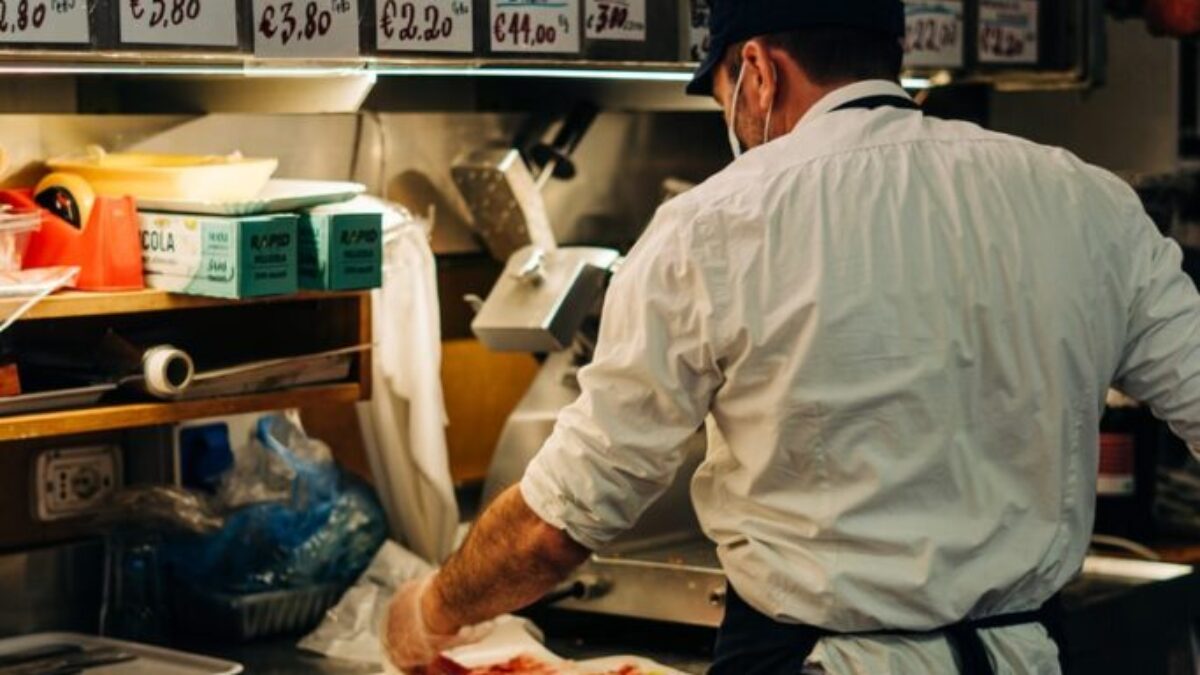 man in white dress shirt standing in front of raw meat