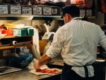 man in white dress shirt standing in front of raw meat