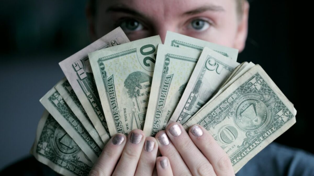 person holding fan of U.S. dollars banknote