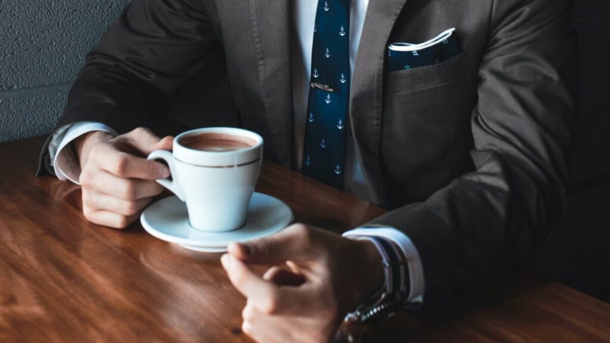 man holding cup filled with coffee on table