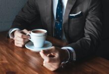 man holding cup filled with coffee on table