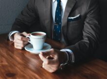 man holding cup filled with coffee on table