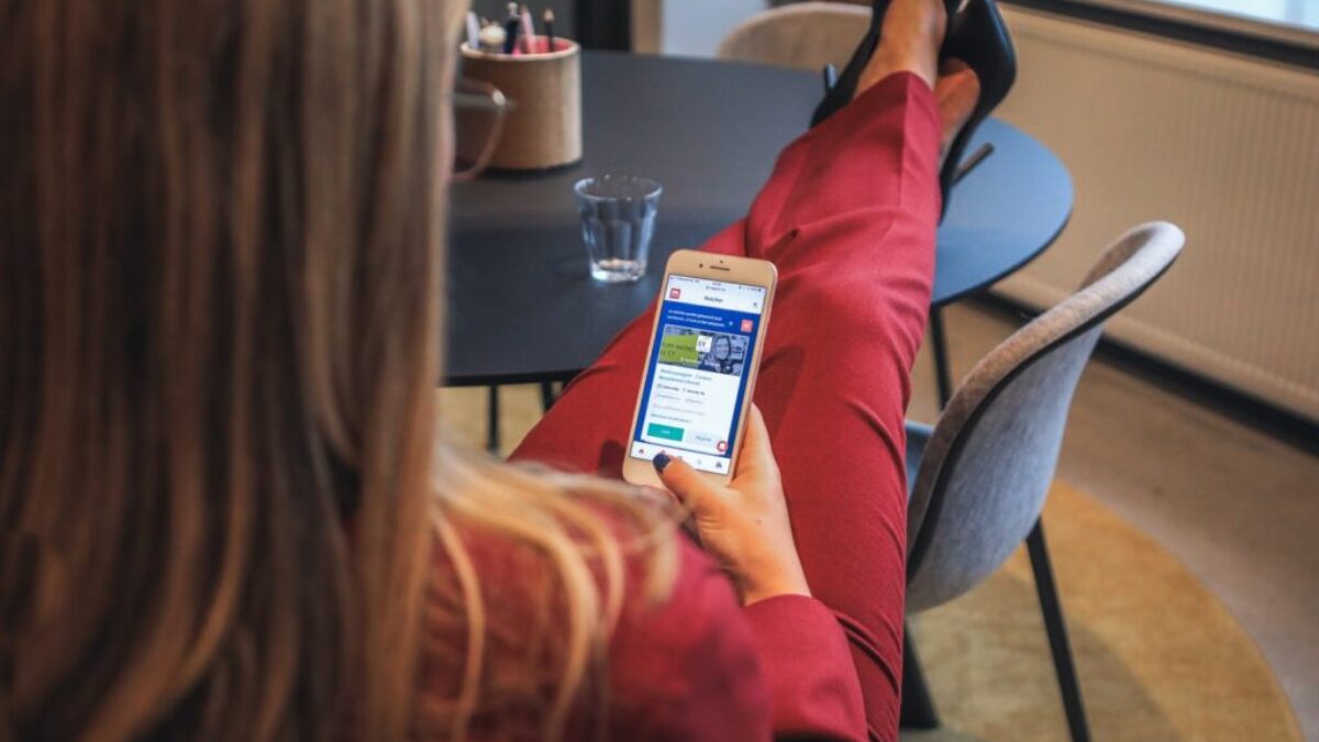 woman in red jacket holding white smartphone