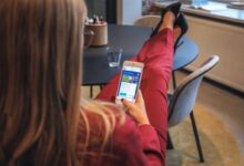 woman in red jacket holding white smartphone