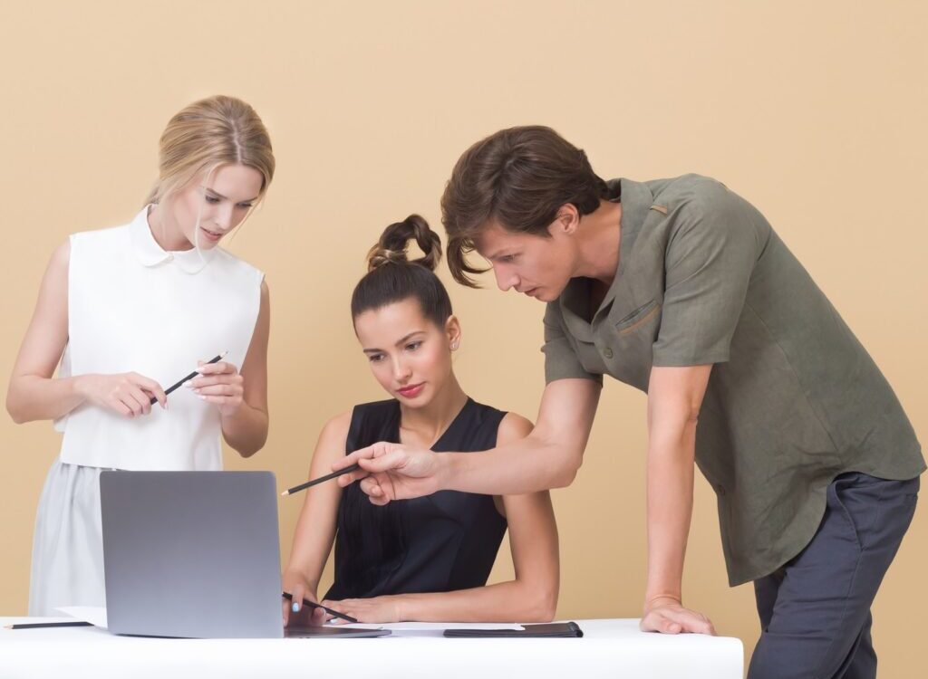 man teaching woman while pointing on gray laptop