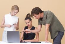 man teaching woman while pointing on gray laptop