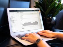 person using macbook air on brown wooden table