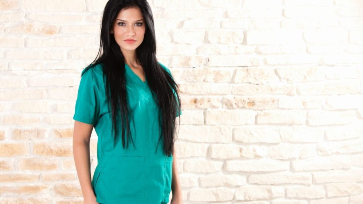 woman in green dress standing beside brick wall