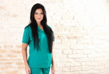 woman in green dress standing beside brick wall
