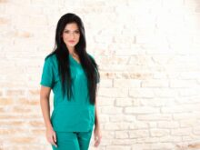 woman in green dress standing beside brick wall
