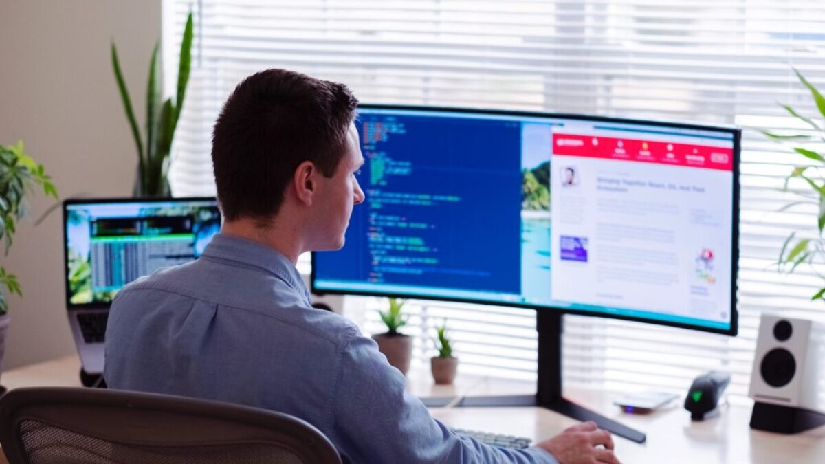 man in gray dress shirt sitting on chair in front of computer monitor