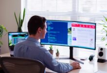 man in gray dress shirt sitting on chair in front of computer monitor
