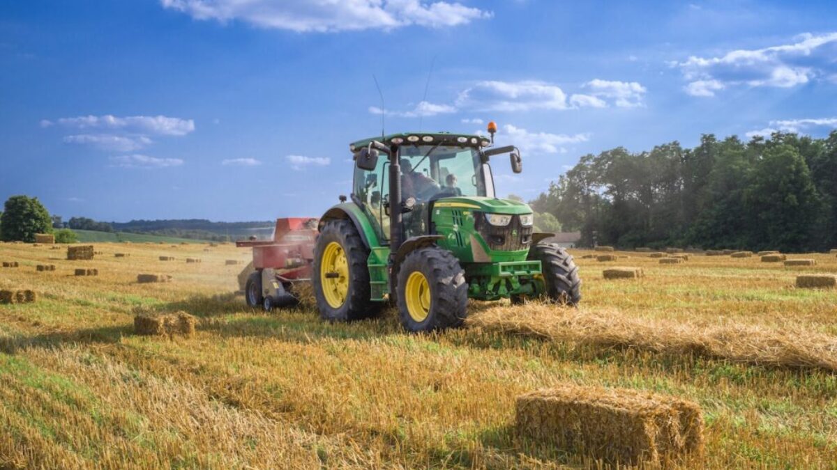 green tractor on brown grass field under blue sky during daytime