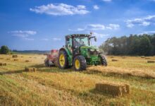 green tractor on brown grass field under blue sky during daytime