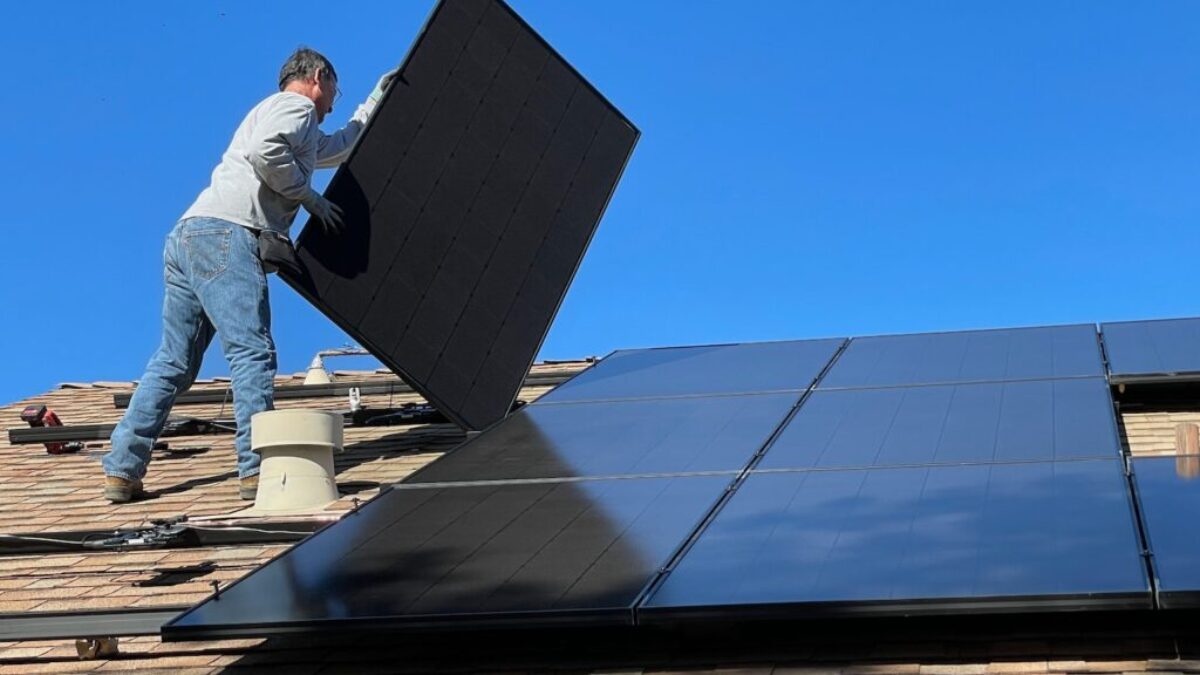 man in white dress shirt and blue denim jeans sitting on white and black solar panel