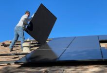 man in white dress shirt and blue denim jeans sitting on white and black solar panel