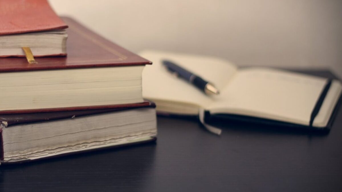 selective focus photography of three books beside opened notebook