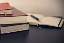 selective focus photography of three books beside opened notebook