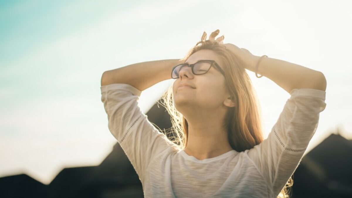 woman in white crew-neck T-shirt holding her head