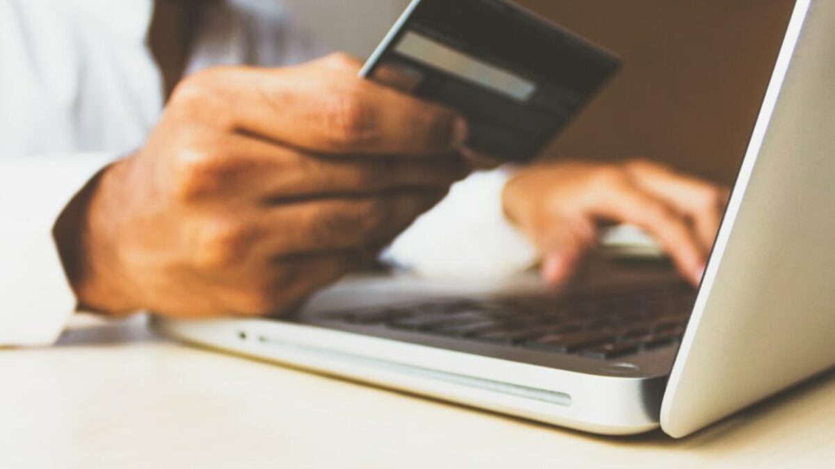 person using laptop computer holding card