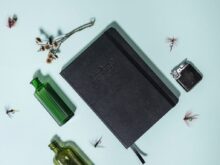 black hardbound book beside bottle