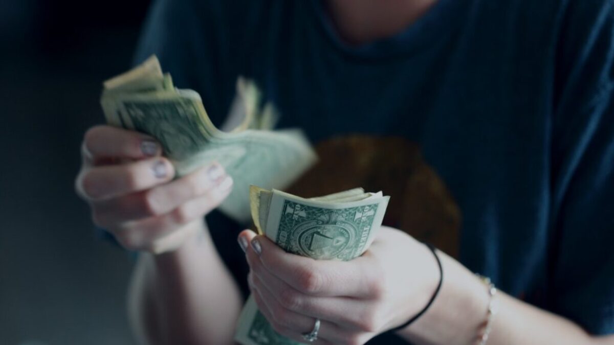 focus photography of person counting dollar banknotes