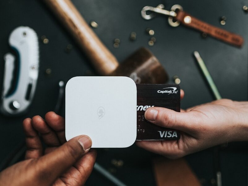 person holding Visa card and white device