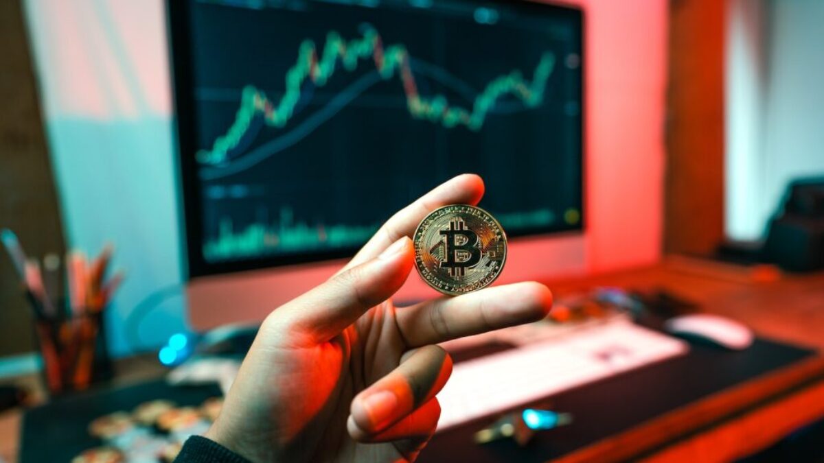 a person holding a coin in front of a computer