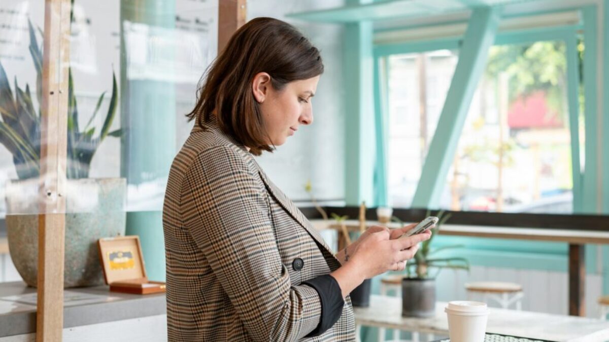 woman in black and white checkered long sleeve shirt using smartphone