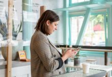 woman in black and white checkered long sleeve shirt using smartphone