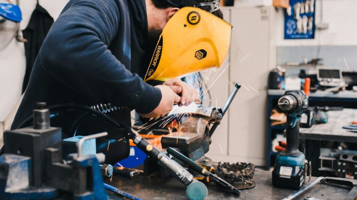 man wearing black hoodie using welding tool