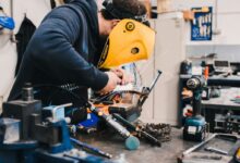man wearing black hoodie using welding tool