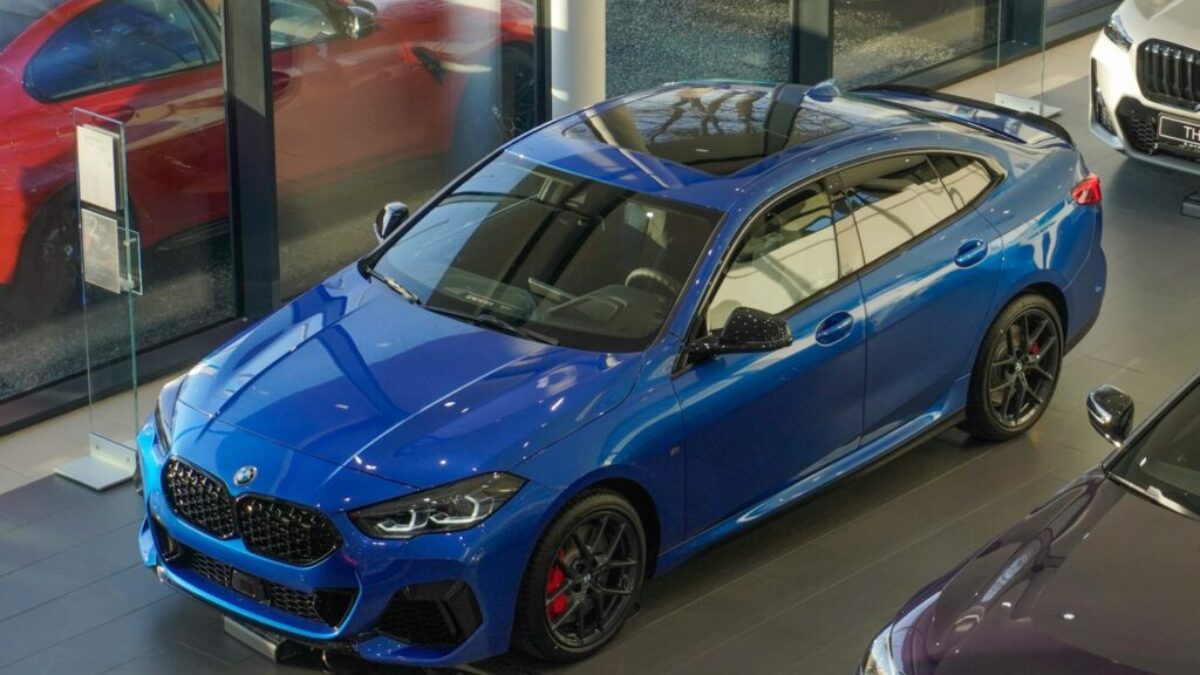 a blue car parked in a showroom next to other cars