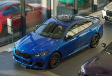 a blue car parked in a showroom next to other cars